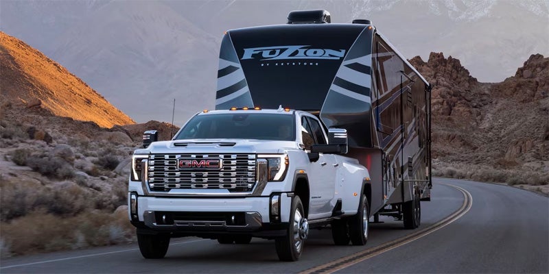 2024 GMC Sierra HD pulling a big trailer while driving down the road